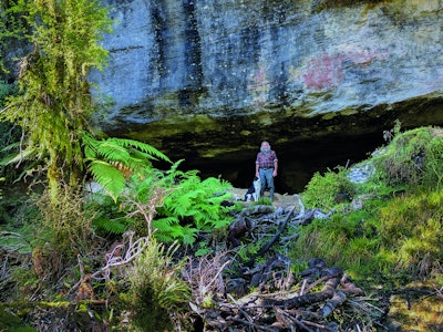 Gids staat met zijn hond in de Maori grot in Nieuw-Zeeland