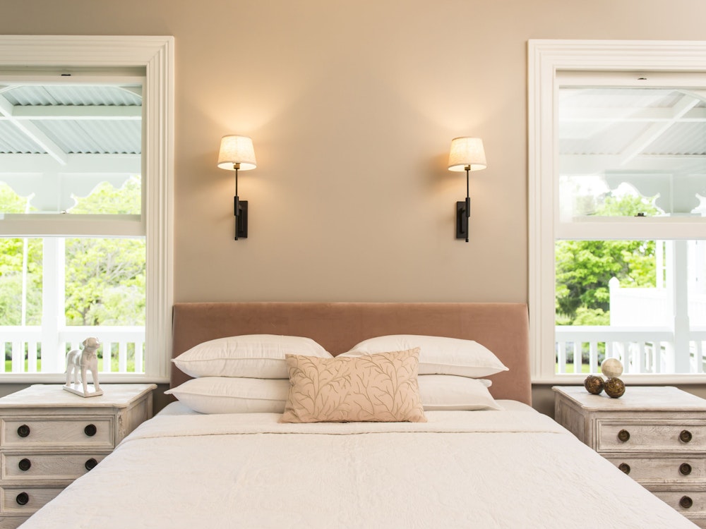 A light, bright bedroom with white linen and large windows