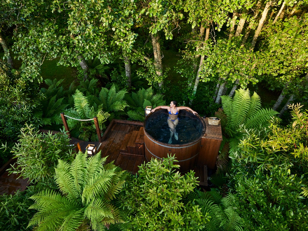 Een vrouw zit in een hot tub in Rotorua midden in de natuur