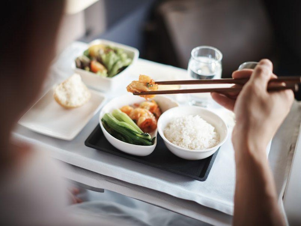 Een reiziger nuttigt een maaltijd tijdens een vlucht in Business Class