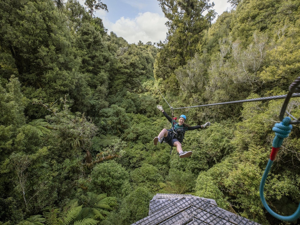 Mann fährt Zipline über Bäume in Neuseeland