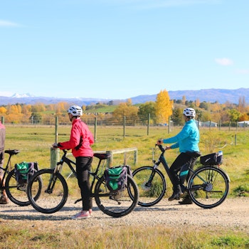 Drie mensen staan met hun fiets te kijken naar de bergen in Otago