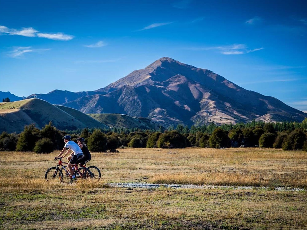 Een fietser fietst over een pad in Wanaka met uitzicht over de bergen