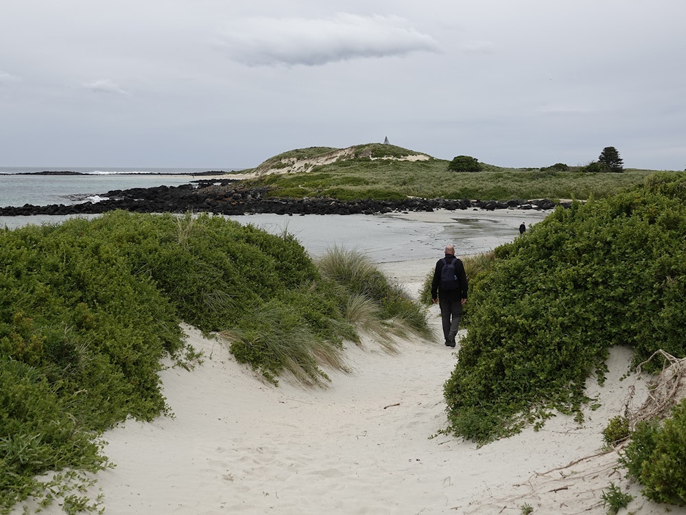 Een man die door duinen wandelt, richting de zee op Griffiths Island