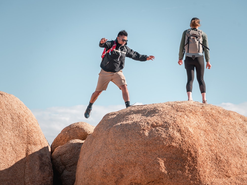Een man springt naar een rots, een vrouw staat op de rots in de VS