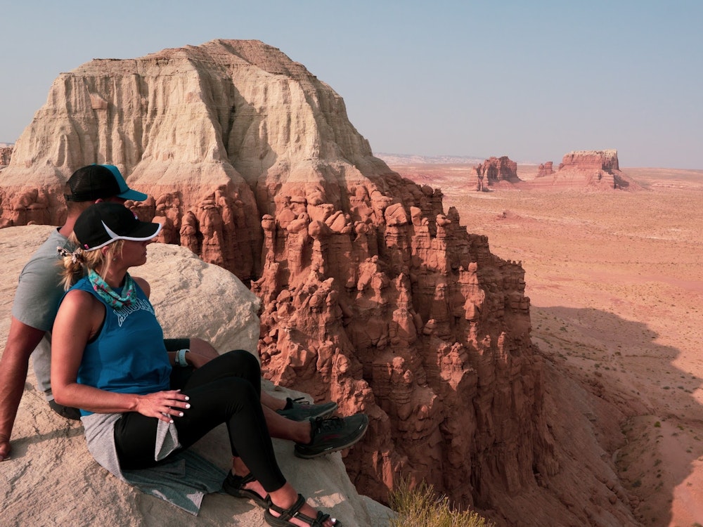 Pärchen sitzt auf Felsvorsprung in roter Felslandschaft in Utah