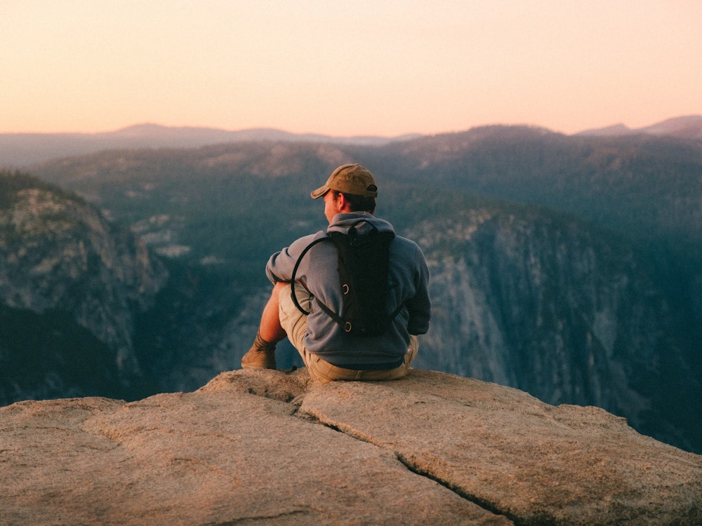 Mann sitz auf Felsvorsprung im Yosemite Nationalpark